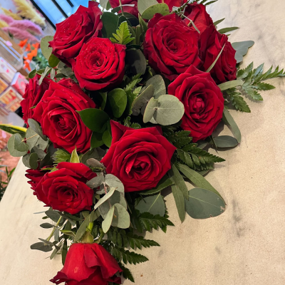 Red Rose Tribute - A heartfelt funeral arrangement featuring rich red roses, elegantly accented with lush greenery. This classic tribute is perfect for expressing deep love and respect, making it a timeless choice for honoring a loved one.